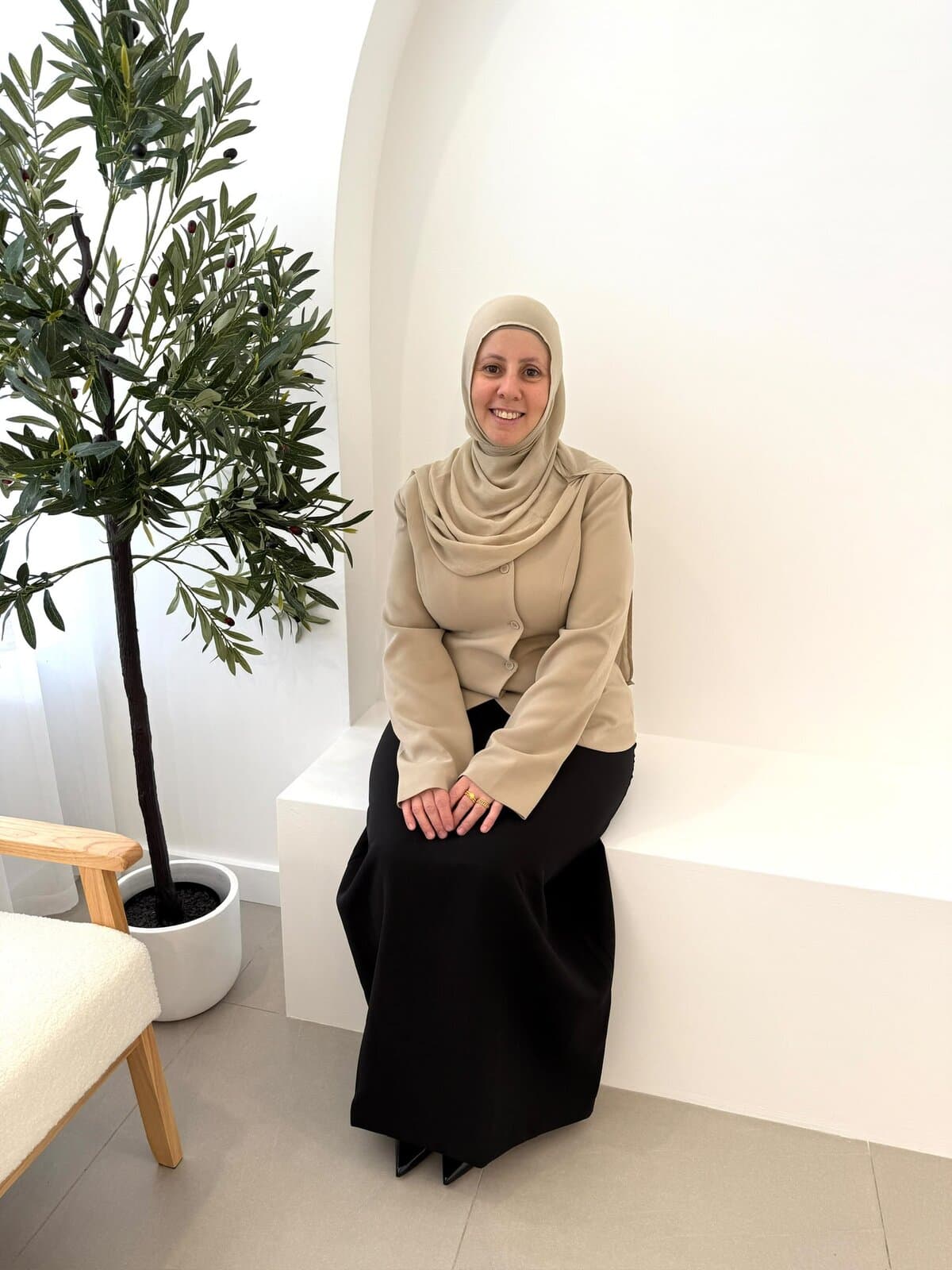 Sara, founder of Trio Cart Academy, smiling while seated beneath a white arch